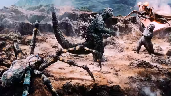 Godzilla battles a giant praying mantis as another monster approaches across rocky terrain