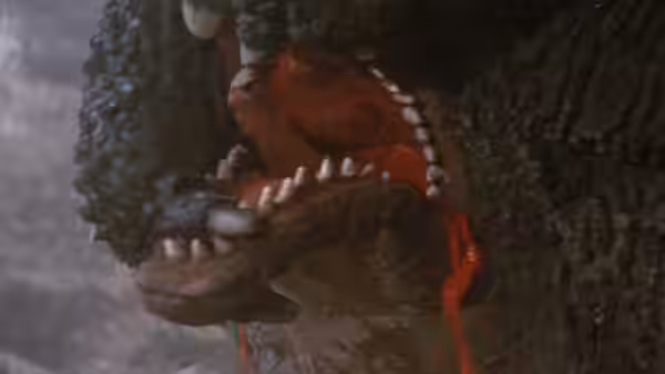 Godzilla's open jaws fill the frame, with red liquid running from its mouth