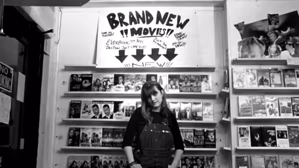 A woman standing in front of shelves in a video rental store