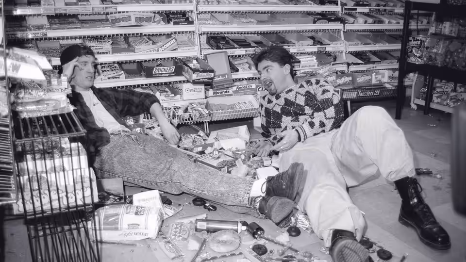 Dante (Brian O'Halloran) and Randal (Jeff Anderson) reclining on the floor of a convenience store amid scattered items