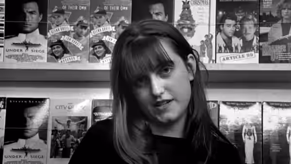 A woman speaking in front of movie posters on a wall