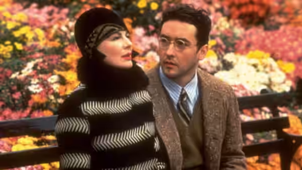 David Shayne (John Cusack) sits with Helen Sinclair (Dianne Wiest) on a bench amid colorful flowers