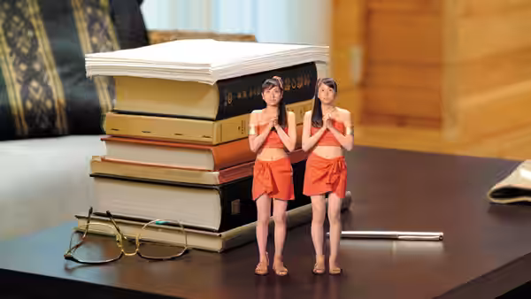 The tiny Shobijin stand beside stacked books and glasses on a table