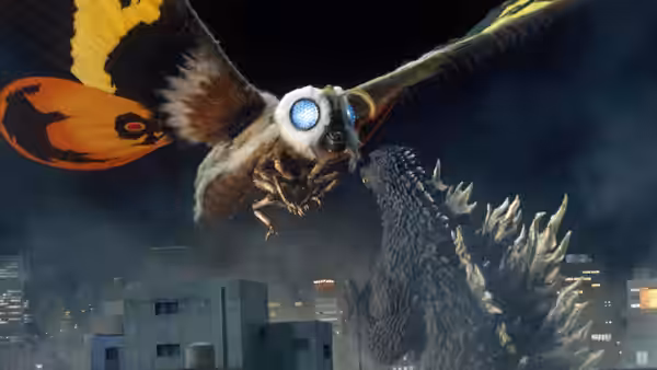 Mothra swoops above Godzilla and city buildings at night