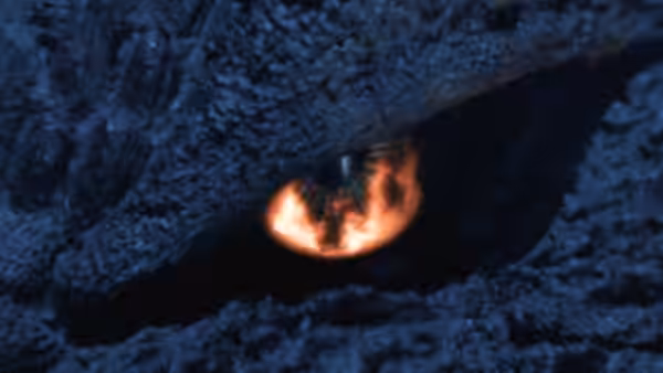A fiery eye peers from beneath Godzilla’s rough, scaled brow