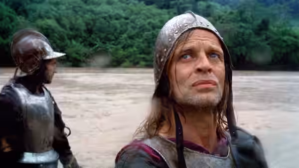 Aguirre (Klaus Kinski) gazing upwards beside a wide muddy river
