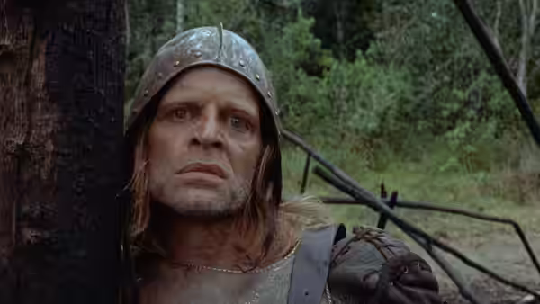 Aguirre (Klaus Kinski) peering from behind a tree in the jungle