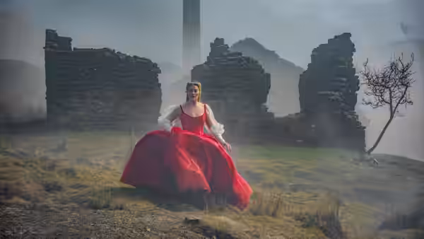 Cathy (Margot Robbie) sits in a red gown among the mist-shrouded ruins