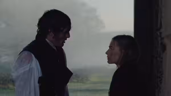 A dark-haired man and a woman face each other in a misty doorway