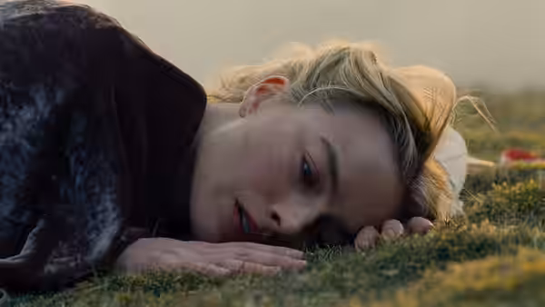 Cathy (Margot Robbie) lies on the grass with her face turned toward the ground