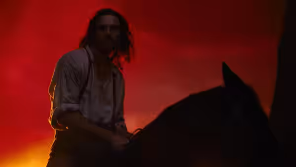 Heathcliff (Jacob Elordi) rides a horse beneath a red-lit sky