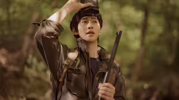 Kang-han (Ahn Hyo-seop) adjusts his cap while holding a rifle in the woods