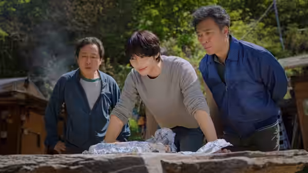 Kang-han (Ahn Hyo-seop) leans over a stone table between two men outdoors