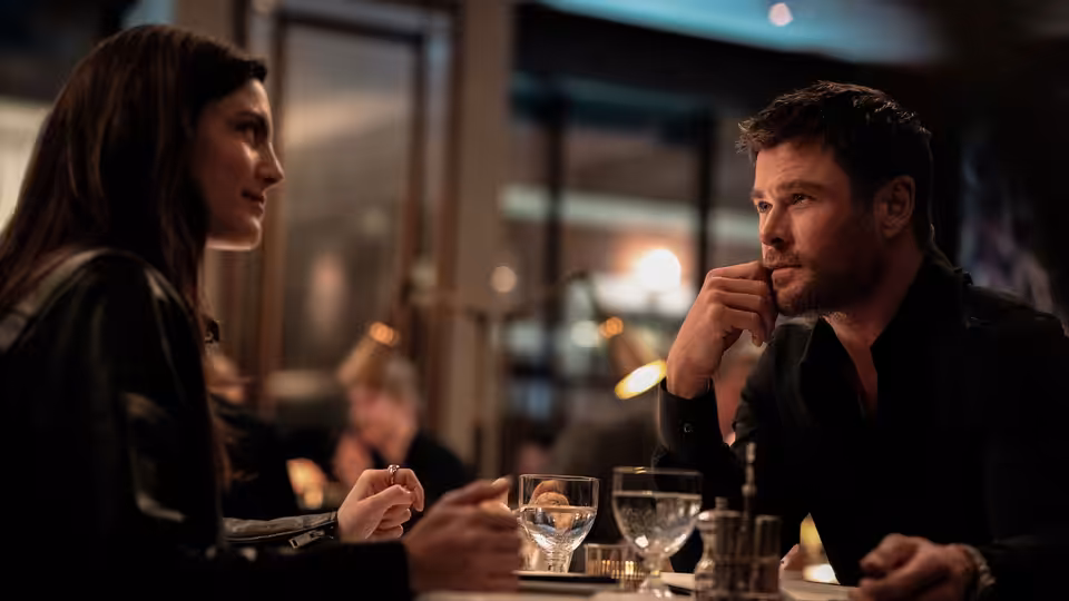 Chris Hemsworth as Davis talks with a woman at a restaurant table
