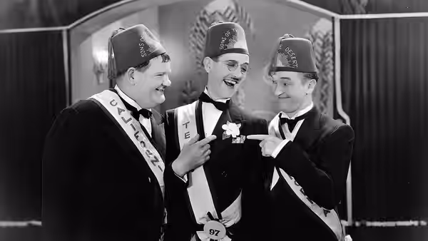 Stan (Stan Laurel) and Ollie (Oliver Hardy) congratulate a fellow lodge member on his sash