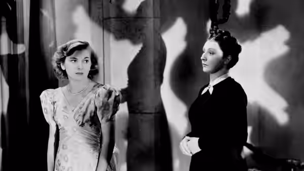 Mrs. de Winter (Joan Fontaine) standing beside Mrs. Danvers (Judith Anderson)