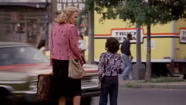 Gloria (Gena Rowlands) stands on a street beside young Phil with a suitcase
