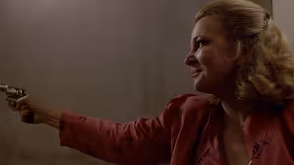 Gloria (Gena Rowlands) points a revolver while glancing to the side