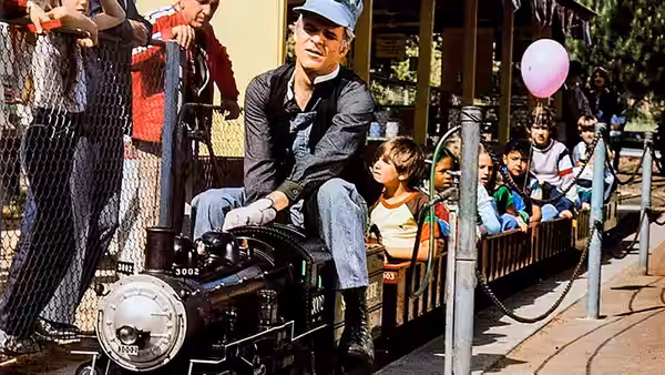 Navin (Steve Martin) drives a miniature train past children at a park
