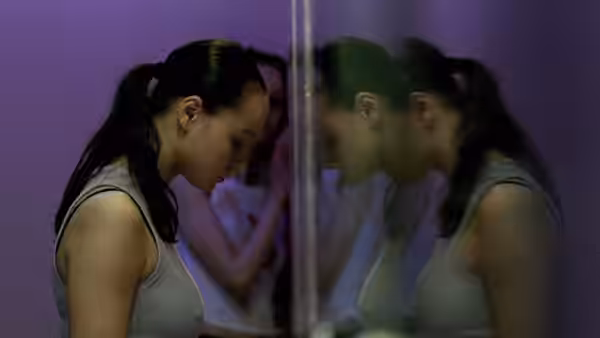 Woman with ponytail looking at her reflection in a mirror