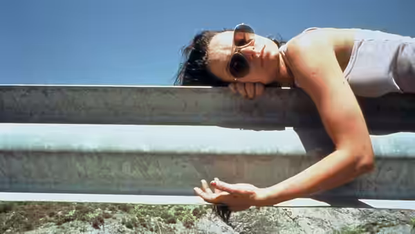 Woman lying on a metal railing wearing sunglasses outdoors