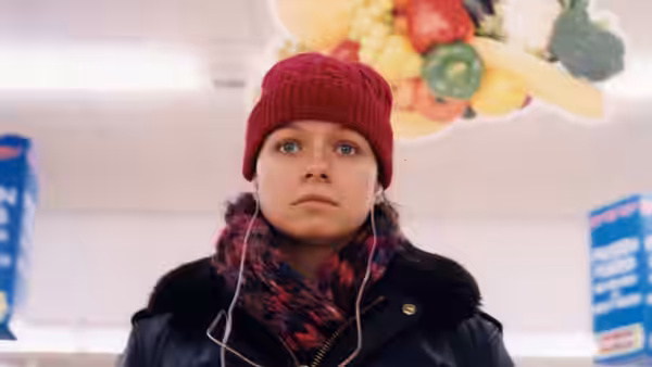 Woman in red beanie and earphones standing in a supermarket