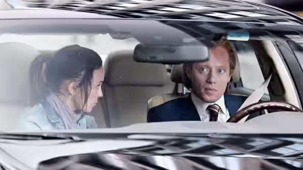 Roger Brown (Aksel Hennie) drives while Diana Brown (Synnøve Macody Lund) looks toward him