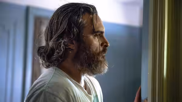 Joe (Joaquin Phoenix) in profile wearing a white t-shirt near a doorway