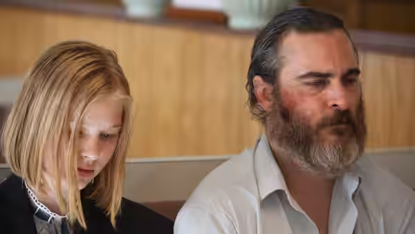 Nina (Ekaterina Samsonov) and Joe (Joaquin Phoenix) seated side by side in a booth