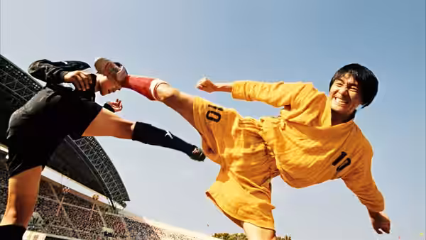 Sing (Stephen Chow) kicks a black-uniformed opponent during a match at the stadium