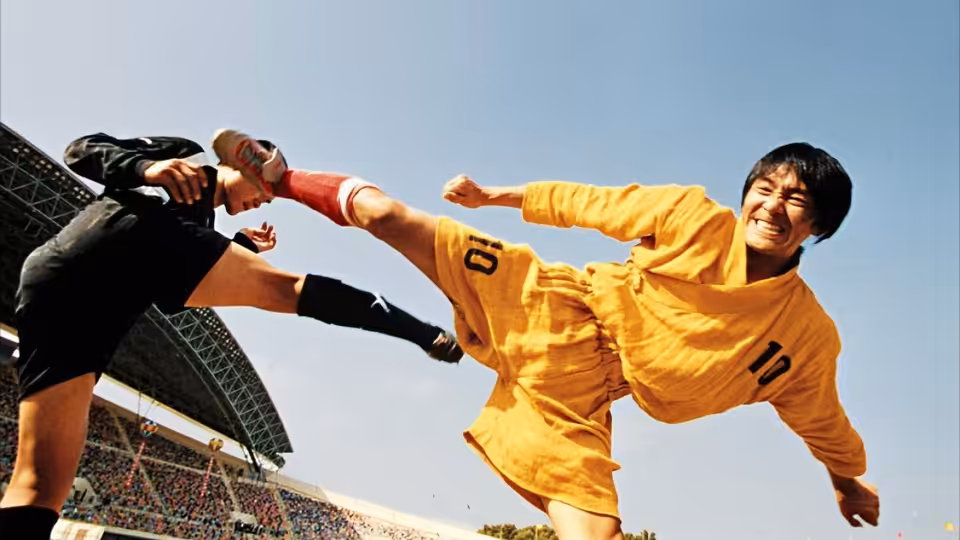 Sing (Stephen Chow) kicks a black-uniformed opponent during a match at the stadium