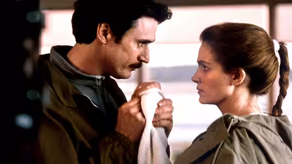 Martin holds a towel while facing Laura inside a seaside home