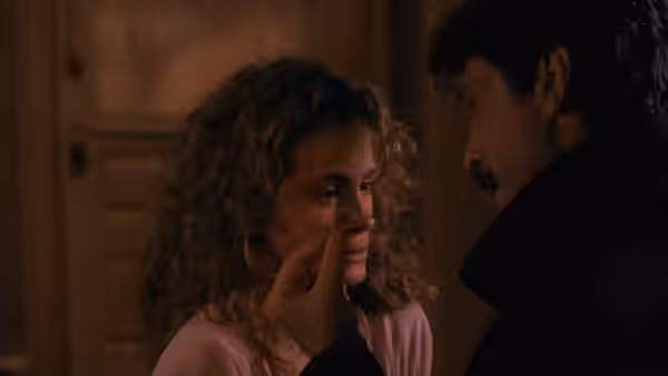 Martin Burney touches Laura's face as she looks away in a dim room