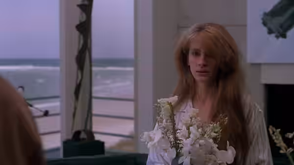 Sara Walters (Julia Roberts) stands holding flowers beside a seaside window