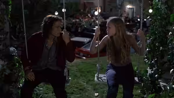 Patrick Verona (Heath Ledger) and Katarina Stratford (Julia Stiles) sit facing on garden swings at night
