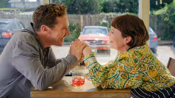 Ivy Rose (Olivia Colman) and Theo Rose (Benedict Cumberbatch) clasp hands across a café table