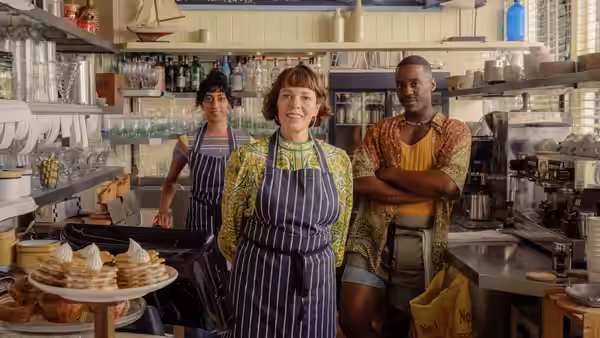 Ivy Rose (Olivia Colman) stands with two workers in a busy bakery