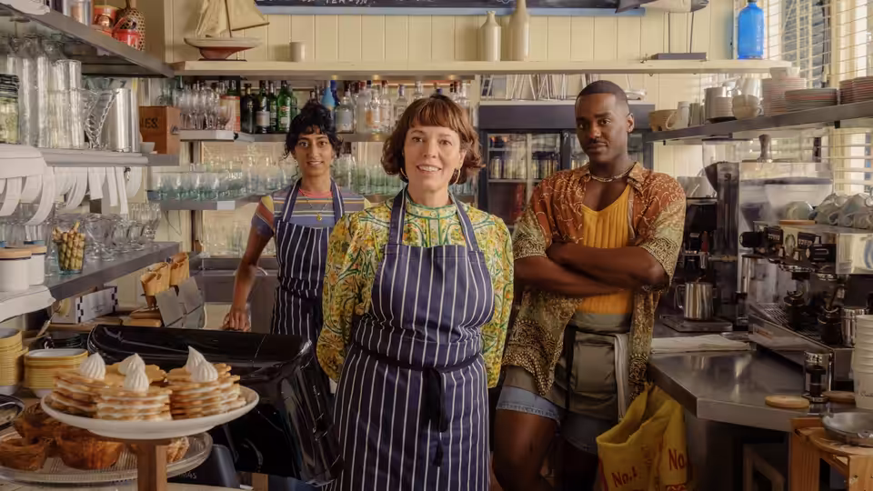 Ivy Rose (Olivia Colman) stands with two workers in a busy bakery
