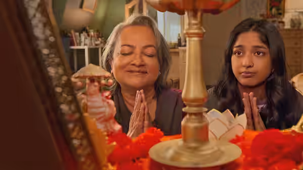 Devi and an older woman pray together at a home altar
