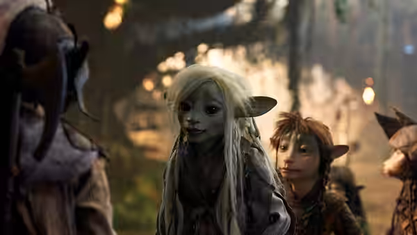 Deet (Nathalie Emmanuel) stands with a young Gelfling among companions in a forest