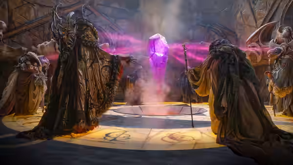 Robed creatures surround a glowing purple crystal in a circular stone chamber