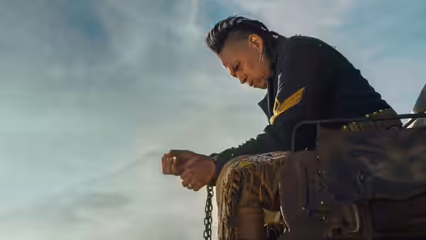 Eli Whipp (Chaske Spencer) sits on a wagon seat, gripping a chain