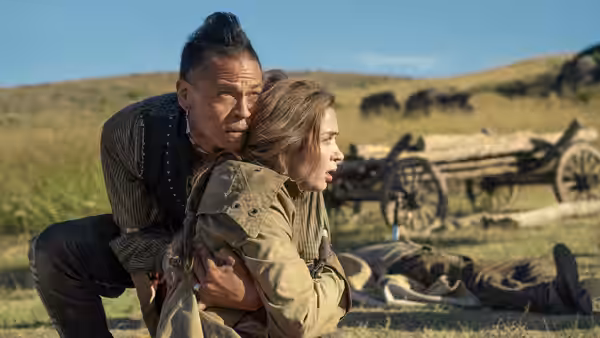 Eli Whipp (Chaske Spencer) holds Lady Cornelia Locke (Emily Blunt) as they crouch beside a fallen man