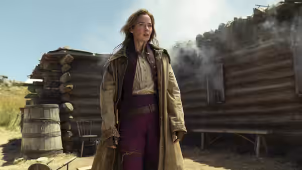 Lady Cornelia Locke (Emily Blunt) stands outside a smoking log cabin in the countryside