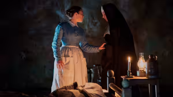 Lib Wright (Florence Pugh) faces a veiled woman beside a candlelit bedside