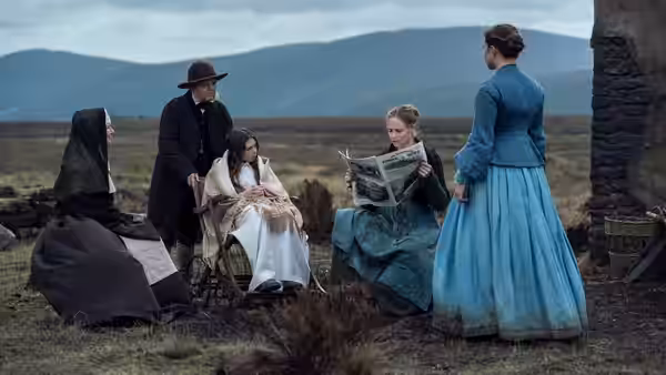 Lib Wright (Florence Pugh) stands near Anna O'Donnell and others gathered outside a stone building