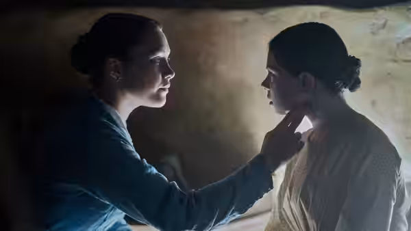 Lib Wright (Florence Pugh) examines Anna O'Donnell's neck inside a shadowy room