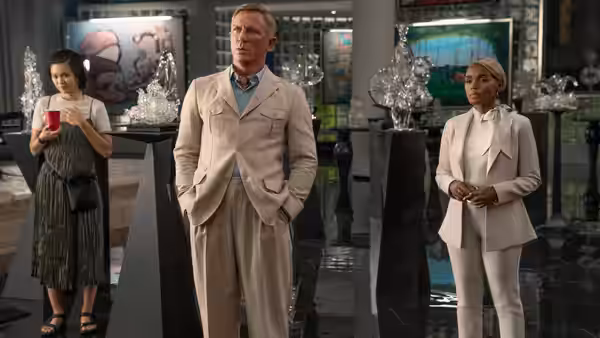 Benoit Blanc (Daniel Craig) stands with Peg (Jessica Henwick) and Andi Brand (Janelle Monáe) in a gallery