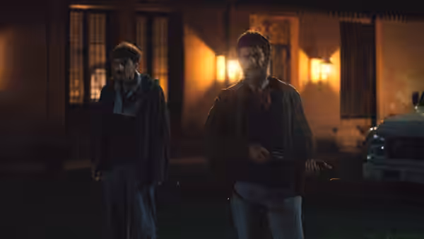 Pedro (Ezequiel Rodríguez) and Jimi (Demián Salomón) stand outside a house, one holding a shotgun