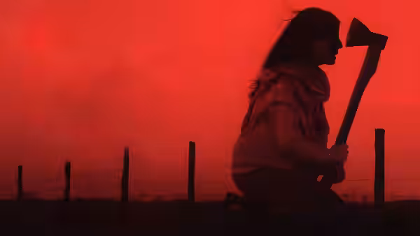 A kneeling figure grips an axe beside a fence under a red sky